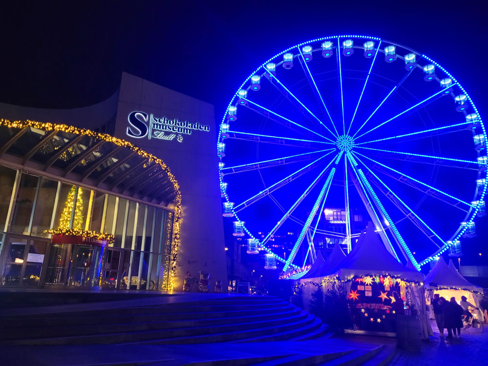 Die Stände des Hafen-Weihnachtsmarktes im Rheinauhafen in Köln sind rund um das Riesenrad aufgebaut